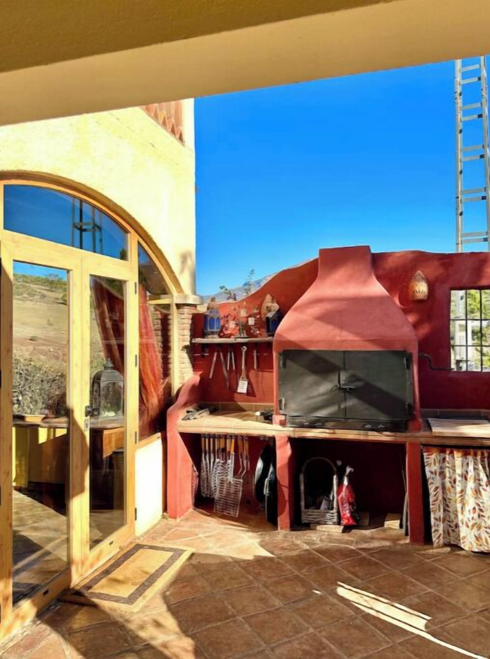 A patio area with a stone floor, a wooden door, a red wall, and a television.