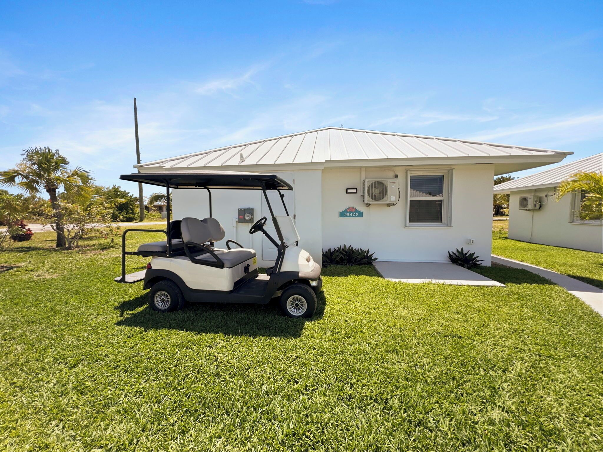 A golf cart parked in front of a small building with a sign that reads "ABACO".