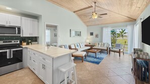 A spacious living area with a kitchen, a ceiling fan, and a view of palm trees. - Golf Cart Included, Andros Villa, Treasure Cay, Bahamas, 100 yards from beach (Treasure Cay)