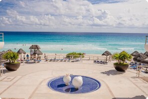 A beach resort with a pool, lounge chairs, and thatched umbrellas. - Luxury 2 beds apartment in front of the beach (Cancún)