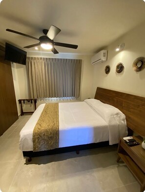 A hotel room with a bed, a ceiling fan, a TV, and a bedside table with a remote control. - Luxury 2 beds apartment in front of the beach (Cancún)