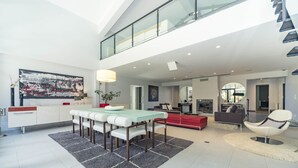 A spacious living area with a high ceiling, a dining table with chairs, a red sofa, and a modern fireplace. - Quiet Villa with wonderful views of the golf courses! (Almada)