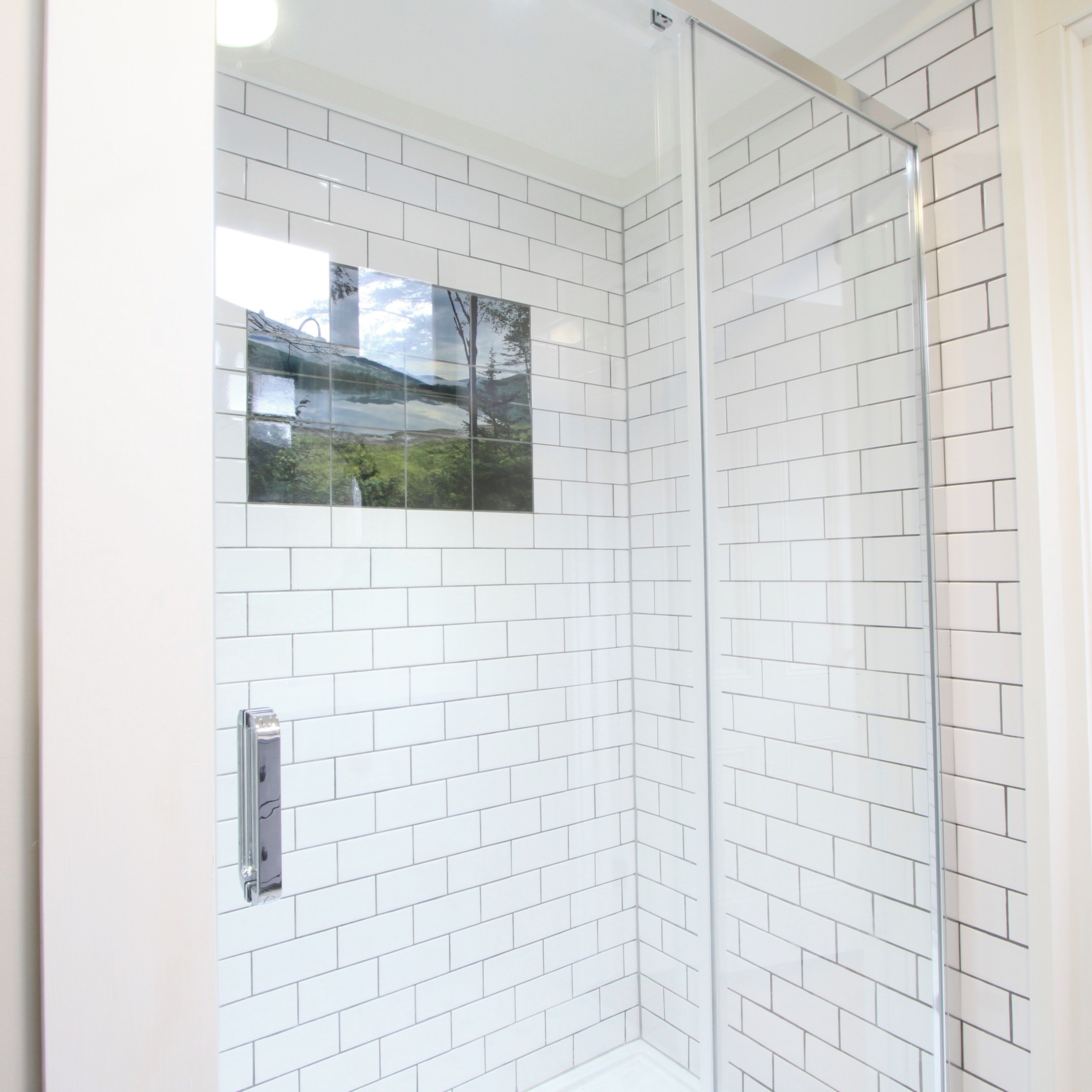 A corner shower with white subway tiles and a glass door.