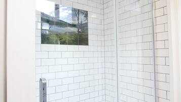 A corner shower with white subway tiles and a glass door.