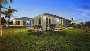 A modern house with a flat roof, large windows, and a well-maintained lawn. - Golf Cart Included, Bimini Villa, Treasure Cay, Bahamas, 100 yards from beach (Treasure Cay)