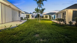 A modern residential complex with multiple houses, a well-maintained lawn, and palm trees. - Golf Cart Included, Bimini Villa, Treasure Cay, Bahamas, 100 yards from beach (Treasure Cay)