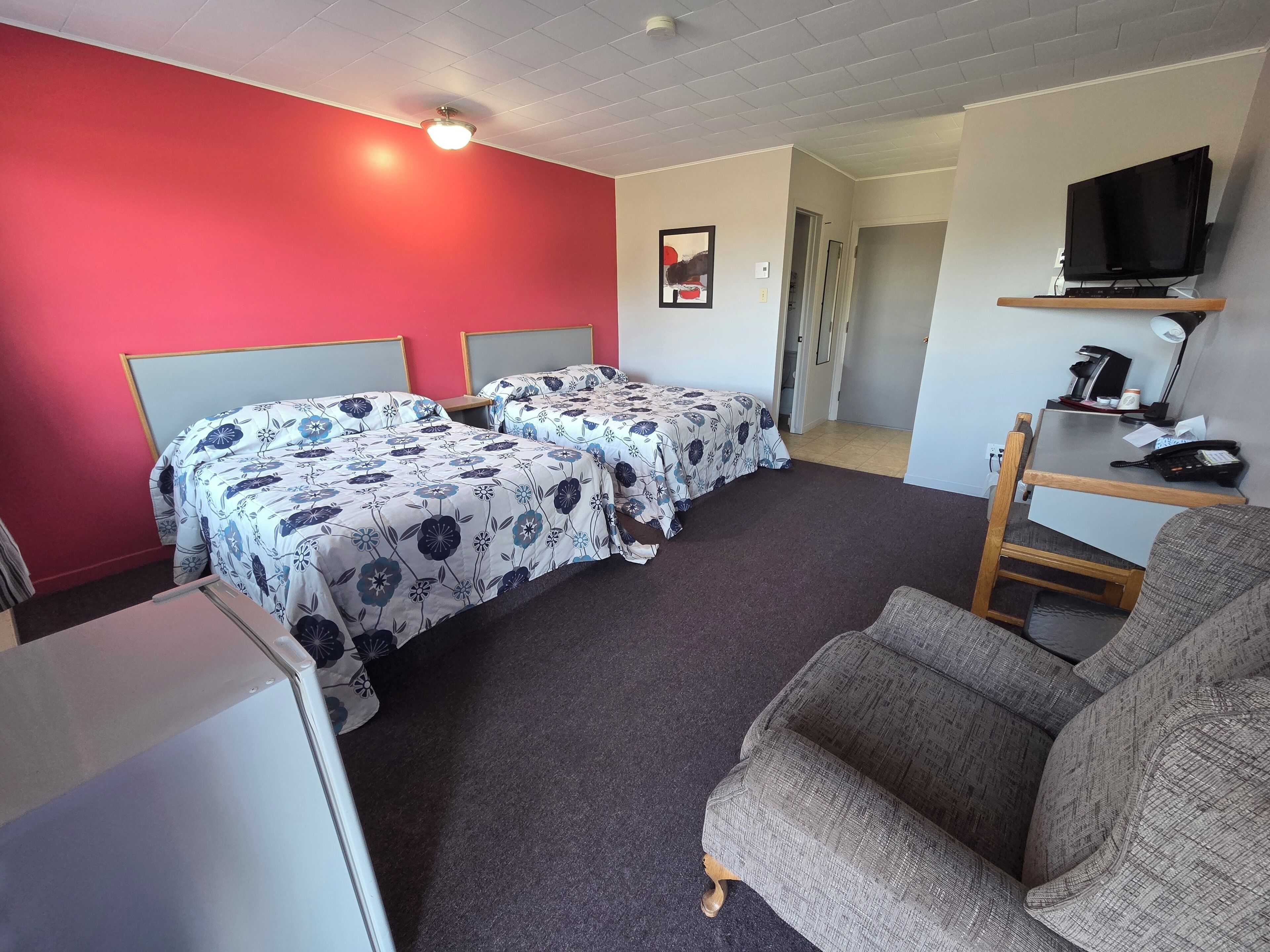 A hotel room with two beds, a TV, a desk, and a chair.