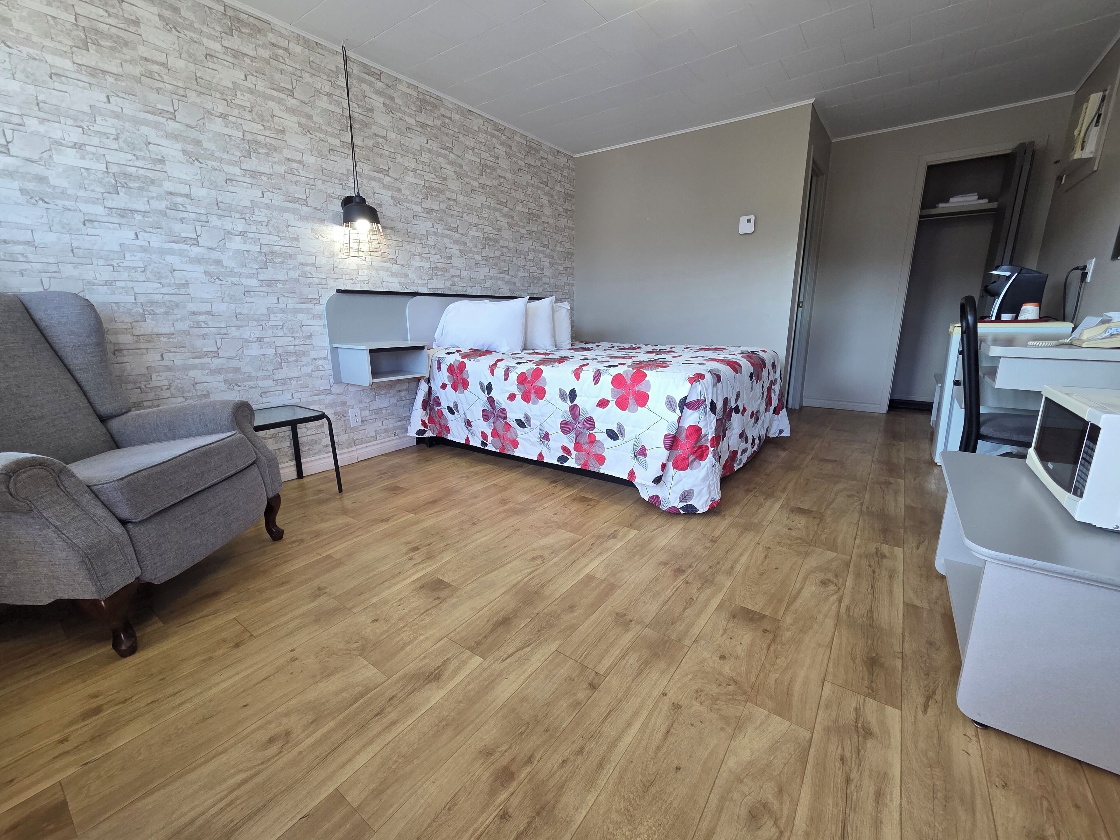 Ein Schlafzimmer mit einem Bett, einem Sessel, einem Schreibtisch und einer Mikrowelle.