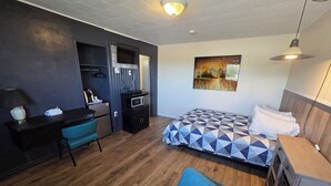 A compact room with a bed, a desk, a chair, a microwave, and a small kitchenette. - Motel Claude (Degelis)