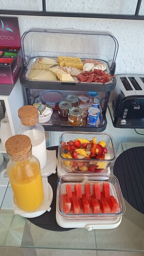 A breakfast buffet with various food items, including fruits, cheeses, and meats.