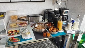 Una mesa de buffet con diversos alimentos, como pan, frutas y salsas.