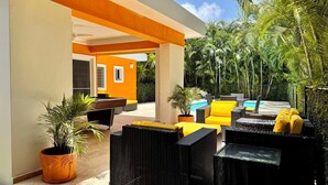 An outdoor lounge area with wicker furniture, yellow cushions, and a pool. - CASA COCO-LOCO Superior 2 Bedroom @ Casa Linda (Sosúa)