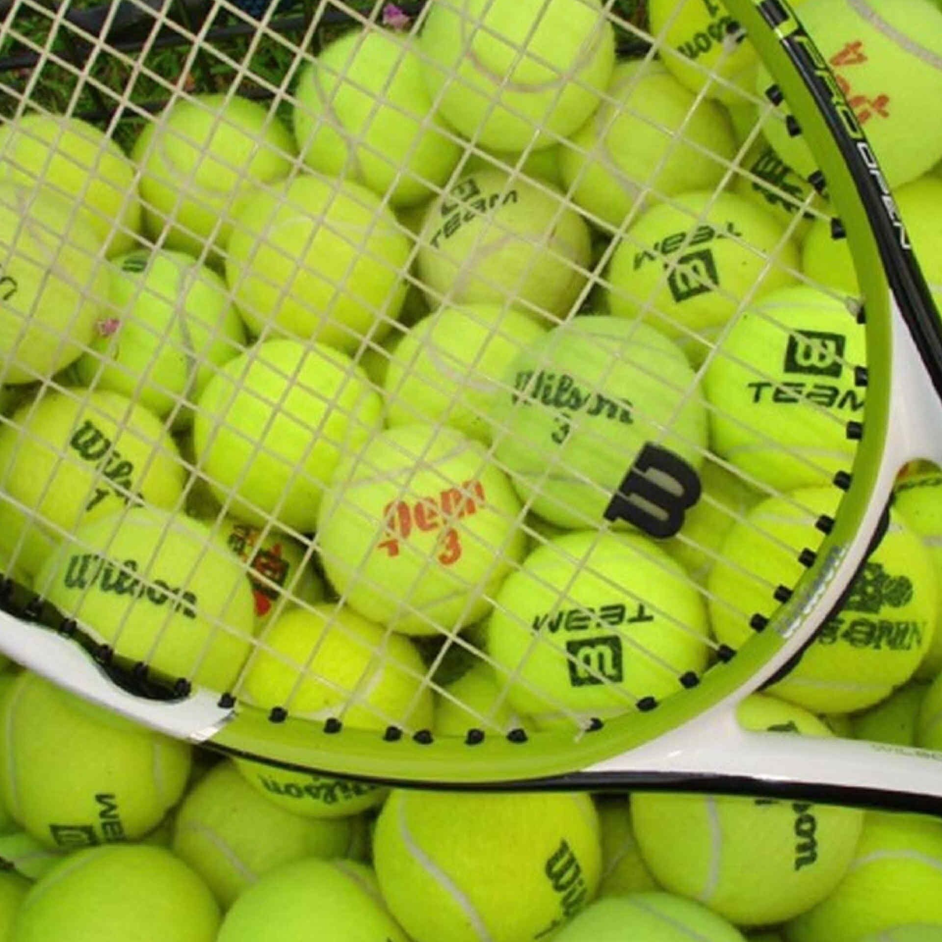 Ein Tennisracket umgeben von Tennisbällen.