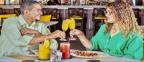 A couple seated at a table in a restaurant with a bar in the background.