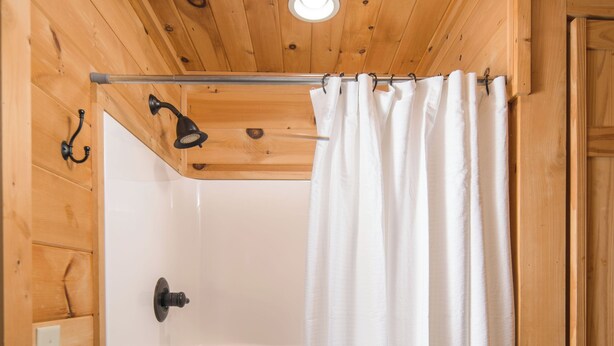 A wooden-paneled bathroom with a shower, white curtain, and patterned floor. - Luxury Cabin centrally located to all the things to see and do in High Country! (Banner Elk)