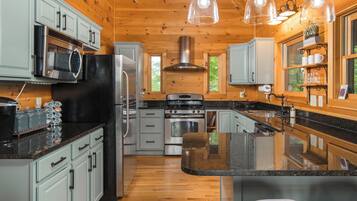 A modern kitchen with wooden walls, stainless steel appliances, and a central island with bar stools.