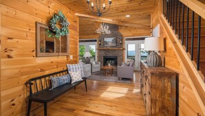 A wooden cabin interior with a fireplace, a bench, a sofa, and a staircase. - Luxury Cabin centrally located to all the things to see and do in High Country! (Banner Elk)
