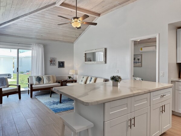 A modern kitchen with a large island, white cabinetry, and a ceiling fan. - Golf Cart Included, Cat Island Villa, Treasure Cay, Bahamas (Treasure Cay)