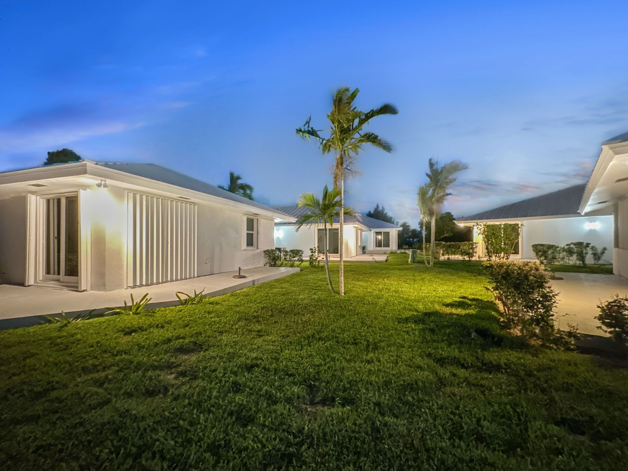 A modern residential complex with multiple houses, each featuring a covered patio and a well-maintained lawn.