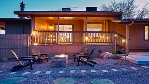 Een huis met een veranda, buitenmeubilair en een vuurkorf.