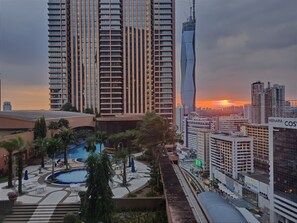 A high-rise building with a pool area and a sunset in the background. - Prime Service Suite At Times Square (Kuala Lumpur)