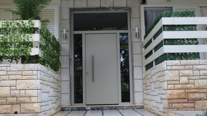 A modern entrance with a double door, stone steps, and a planter with greenery.
