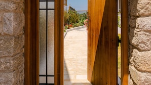 Une entrée en pierre, avec une porte en bois et un grand portail en bois.