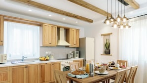 Une cuisine moderne avec des meubles en bois, une table à manger pour quatre personnes et un luminaire suspendu.