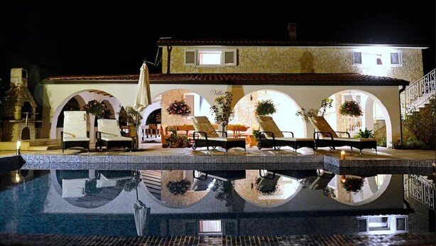 Area piscina con lettini e un edificio in pietra con archi.