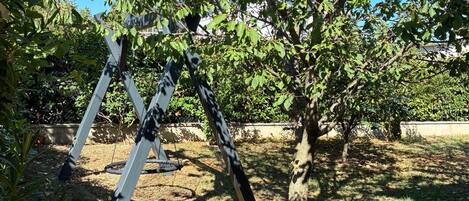 A tree with a swing set in a backyard.