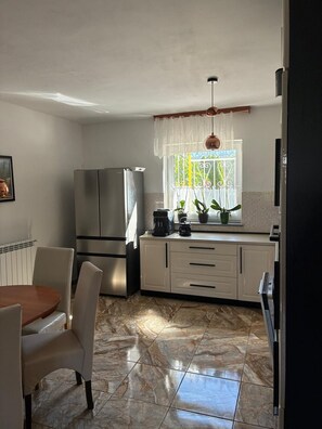 A modern kitchen with a refrigerator, stove, and dining area with chairs.