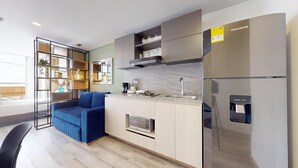 A modern kitchen with a built-in microwave, a refrigerator, and a coffee machine. - gA Distintivo Loft en Cabrera (Bogotá)