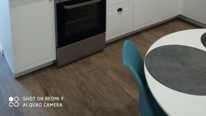 Une cuisine compacte équipée d’une cuisinière à gaz, d’un four et d’un évier. On peut voir une machine à café sur le plan de travail, ainsi que divers ustensiles de cuisine.