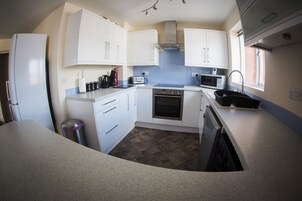 A compact kitchen with white cabinets, a built-in oven, a microwave, and a sink.