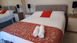 Een hotelkamer met een groot bed, twee nachtkastjes en een bedtafel.