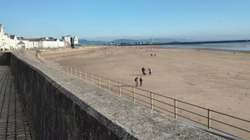 A beach with a stone wall and buildings in the background.