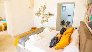 A bedroom with a bed, a wall-mounted mirror, and a bathroom visible through an open door. - Villa Angelita by Villa Plus (Ceglie Messapica)