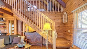 A wooden interior with a staircase, a sofa, a table, and a lamp. - Peaceful Waters Ridge on the Soque River (Demorest)