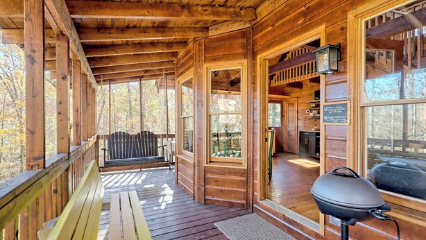 A wooden cabin with a covered porch, a grill, and a bench. - Peaceful Waters Ridge on the Soque River (Demorest)