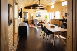 Un accogliente interno di una baita con zona pranzo, cucina e soggiorno.