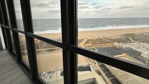 Uitzicht vanuit een hoog gebouw op een strand met een parkeerplaats en een omheind gedeelte.