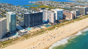 Een kusthotel met meerdere hoge gebouwen, een zandstrand en een zwembad.