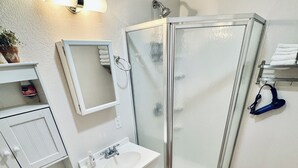 Een badkamer met toilet, wastafel, spiegel, douche en een handdoekrek.