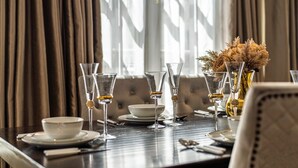 A dining table set with multiple glasses, a bowl, and a vase with dried flowers. - The Mayfair Collection (London)