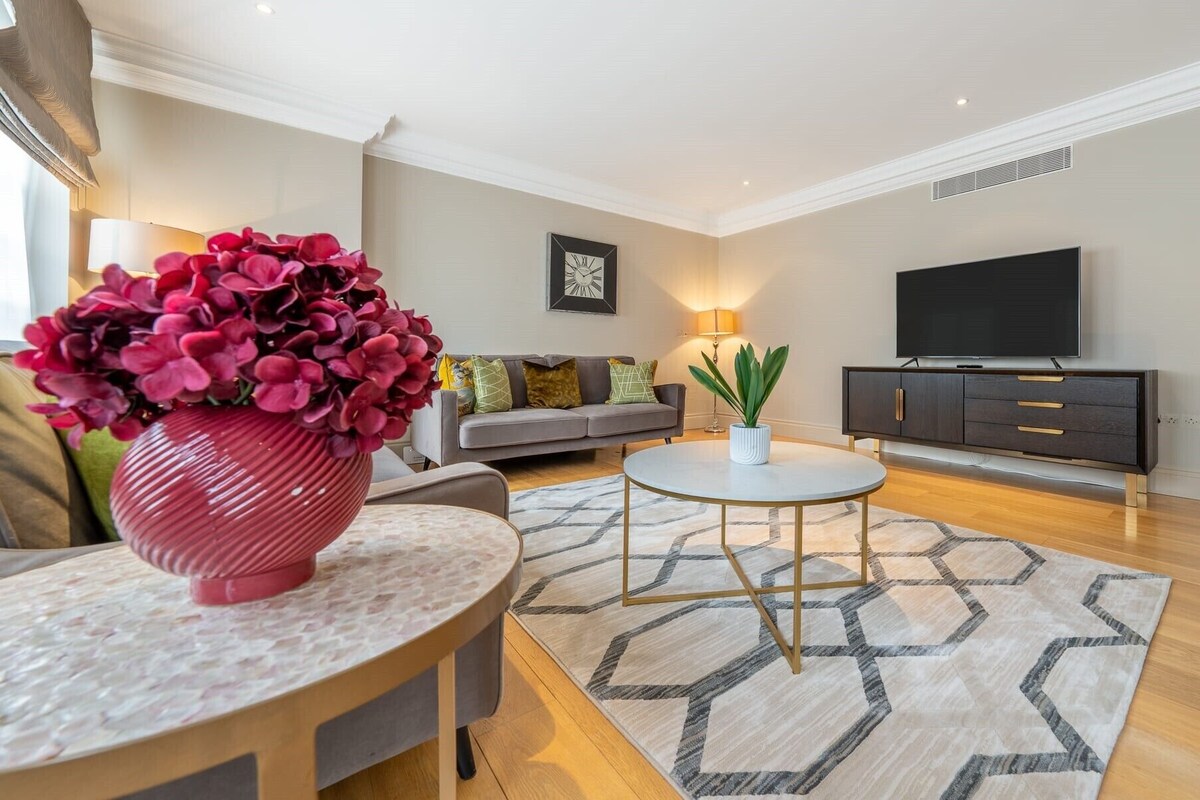A modern living room with a sofa, a coffee table, a TV, and a decorative vase.