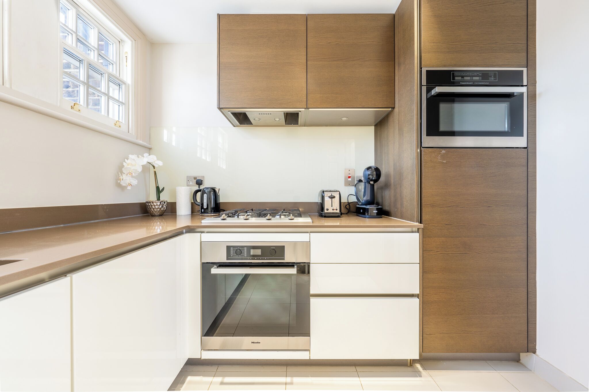 A modern kitchen with a built-in oven, a dishwasher, and wooden cabinets.