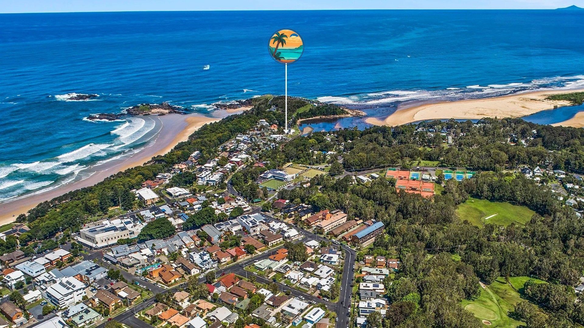 An aerial view of a coastal town with residential buildings, a beach, and a golf course.