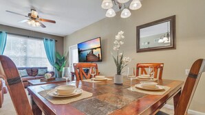 A dining area with a wooden table set for four, surrounded by chairs. - Disney 2 miles w/Heated Pool, water park, basketball tennis courts,  game room  (Kissimmee)