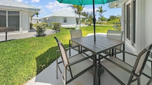 Een terras met een tafel, stoelen, een parasol en uitzicht op omliggende huizen en groen.