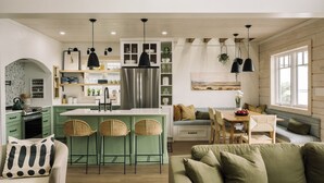 A modern kitchen with green cabinets, a stainless steel refrigerator, and a central island with bar stools. - Riverside Cabin 4
A serene riverside getaway (Campbellford)